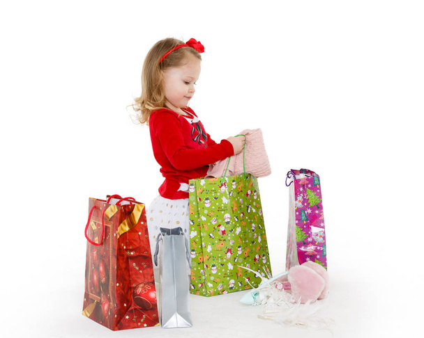 Happy pretty little child with shopping bags sits on a white background. 3 year old. - Photo, Image