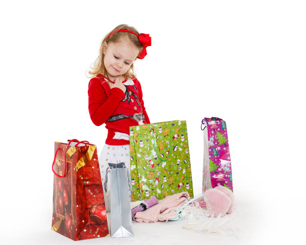 Happy pretty little child with shopping bags sits on a white background. 3 year old. - Foto, Imagem