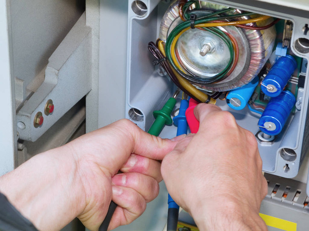 hands of an electrician with electrical test instrument to a switch box - Foto, Imagen
