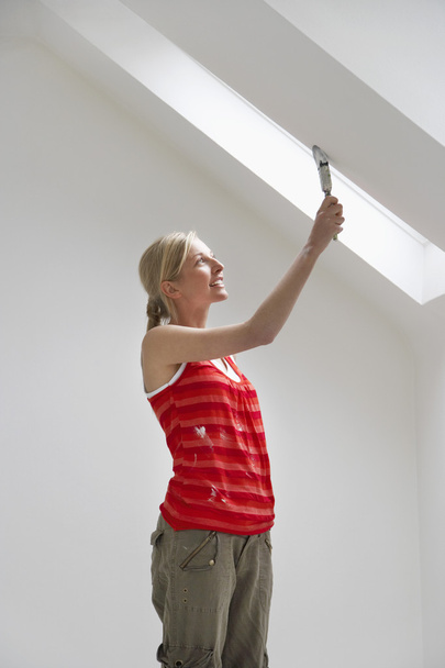 Woman painting sloping ceiling - Foto, immagini