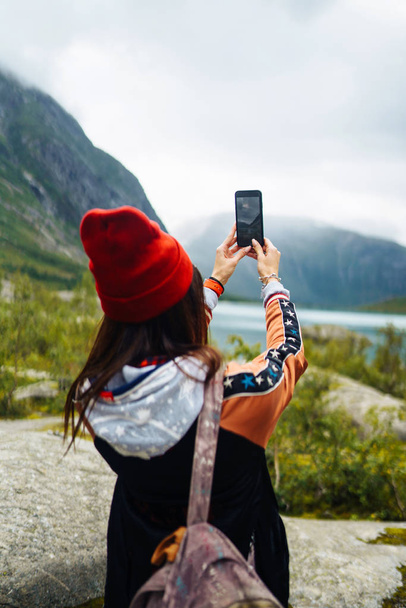 Stylish woman takes a photo on the phone in the travelling. The girl tourist photographs a picturesque landscapes.Travelling, lifestyle, adventure, concept. - Photo, image