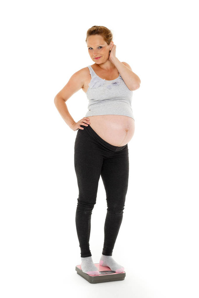 Young  pregnant woman with scales on a white background. - Foto, Bild