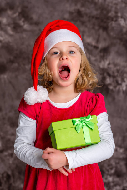 little girl with Santa- cap and present - Фото, зображення