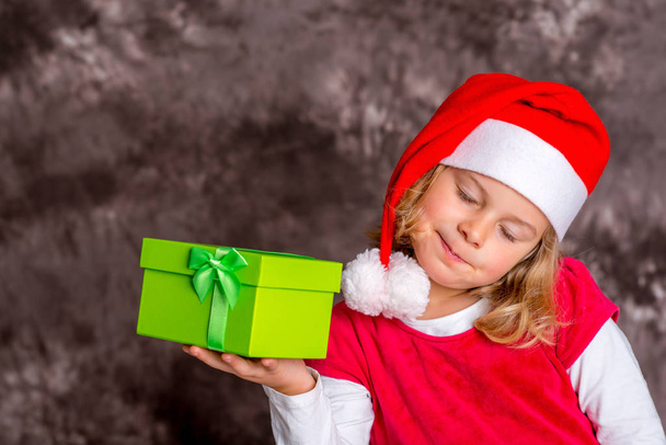 little girl with Santa- cap and present - Φωτογραφία, εικόνα