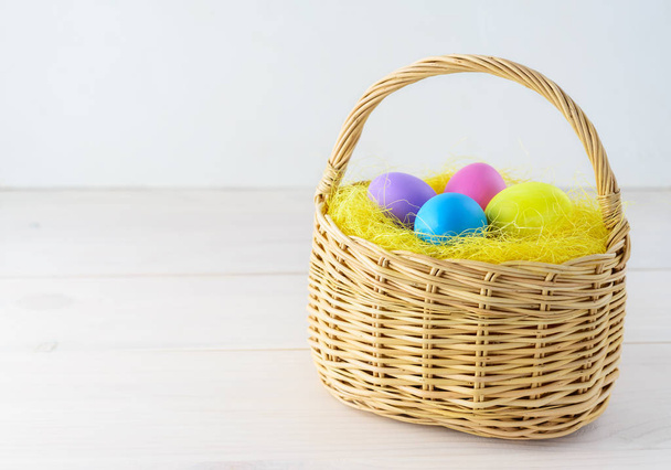 Easter eggs in a basket on a wooden table. Horizontal orientation, copy space. - Foto, Bild