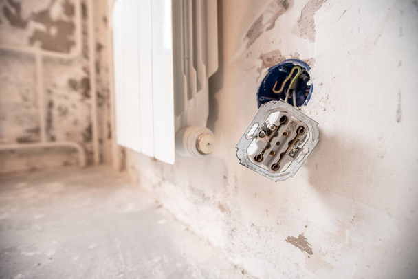 Rozebrané elektrické zásuvky v detonační stěně s holými dráty a puncovními značkami při opravě v bytě - Fotografie, Obrázek