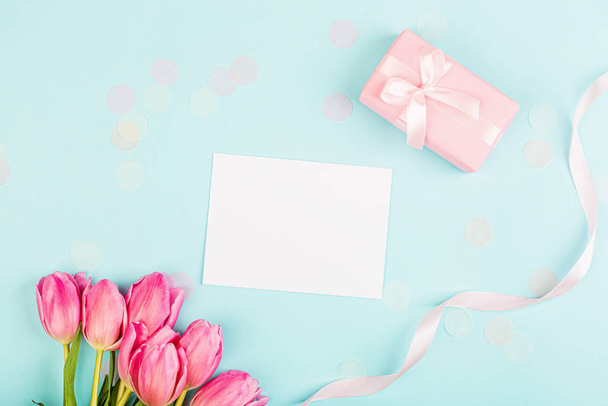 View from above tulips and gift box with copy space on blue. Background for womens day, 8 March Valentine's day, 14 february. Flat lay style, top view, mockup, template, overhead. Greeting card - 写真・画像