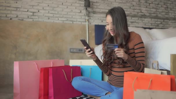 видео красивой азиатской женщины, делающей электронные покупки дома - Кадры, видео
