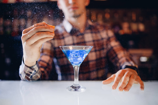 Μεγάλο κοκτέιλ σε ποτήρι μαρτίνι με σταγονίδια σπρέι παρασκευάζεται από τον μπάρμαν - Φωτογραφία, εικόνα