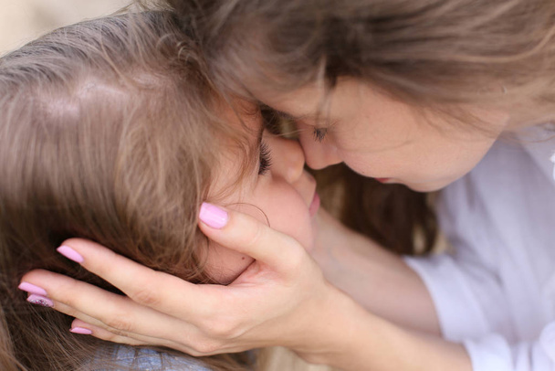 Мама касается лица своей маленькой дочери.
 - Фото, изображение