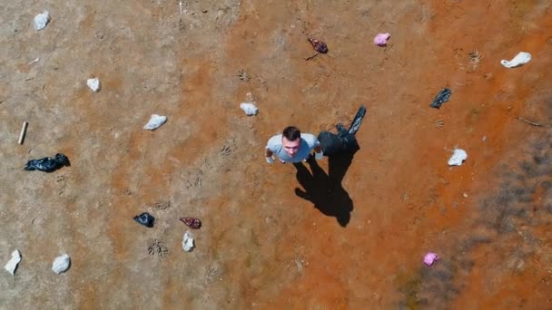 Aerial top view of man who stands along plastic trash on banks of polluted river - Footage, Video
