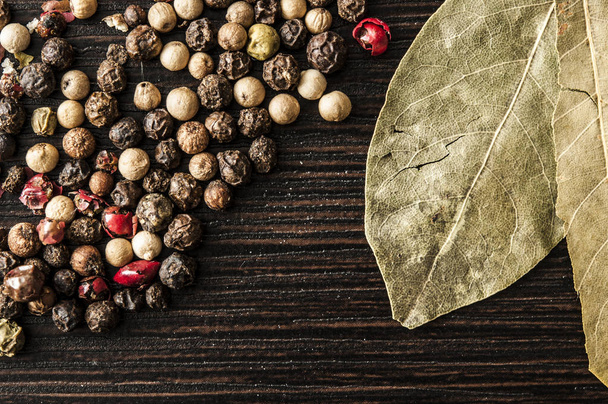 bay leaf on a black background with black pepper peas - Foto, afbeelding