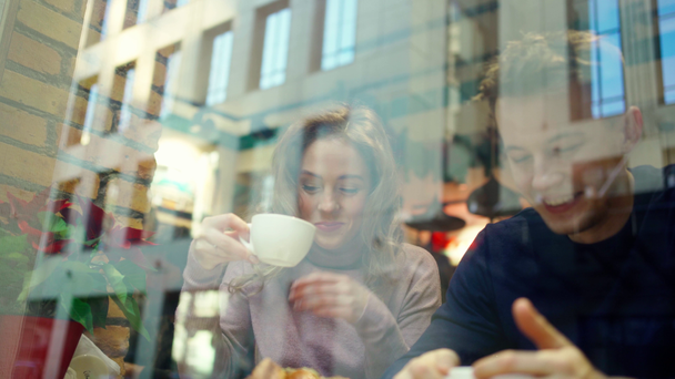 nuori kaunis pari mies ja nainen treffeille viihtyisässä kahvilassa, puhuminen, kahvin juominen ja hauskaa yhdessä
. - Materiaali, video