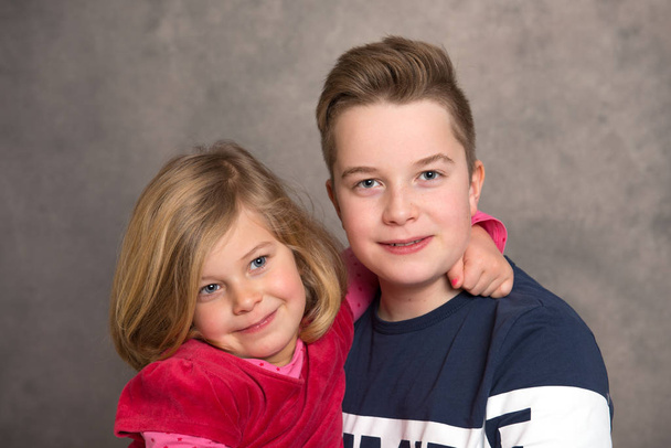 brother and sister together in front of gray background - Photo, image