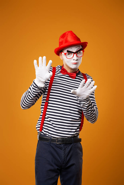 Mime looking at camera in vest and red hat Isolated on orange background - Fotó, kép
