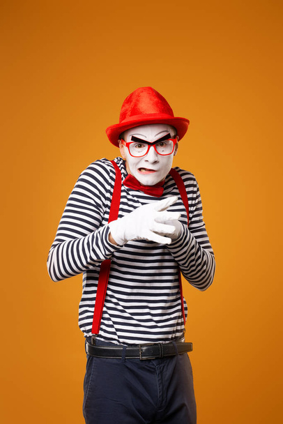 Mime man looking at camera in vest and red hat Isolated on orange background - Фото, изображение