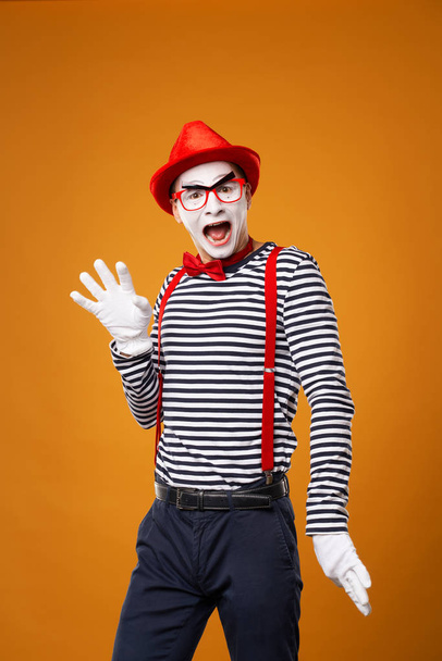 Smiling mime man looking at camera in vest and red hat Isolated on orange background - Valokuva, kuva