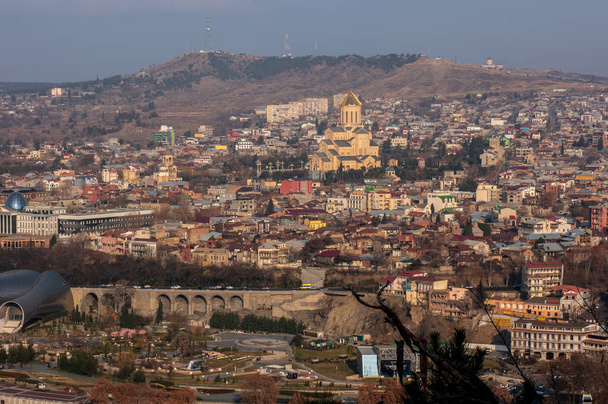 Tbilisi, Georgia - December 31 2019: Beautiful view of Kura river and Bridge of Peace in Tbilisi. Bridge is a bow-shaped pedestrian bridge in Tbilisi - Фото, зображення