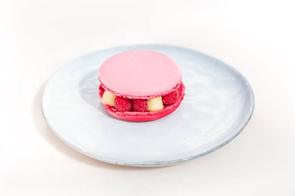 Macaron rose avec framboise sur une assiette
 - Photo, image