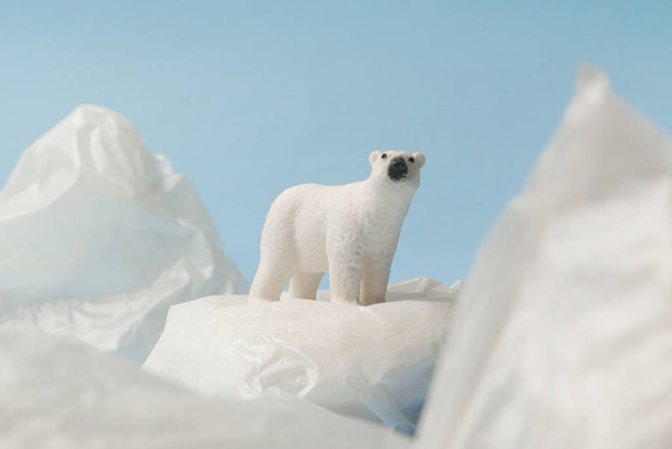 青い背景のビニール袋に白いホッキョクグマ、プラスチック汚染と気候変動の概念 - 写真・画像