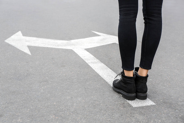 Giovane donna in piedi sulla strada con frecce marcatura. Concetto di scelta
 - Foto, immagini