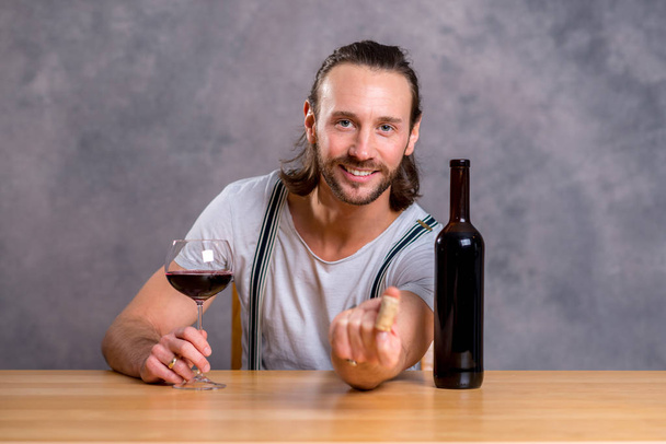 young man sitting at the table and drinking red wine - Foto, Imagen