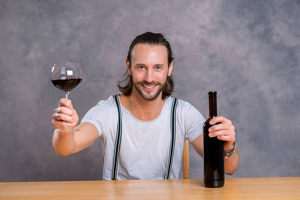 young man sitting at the table and drinking red wine - Foto, Imagem