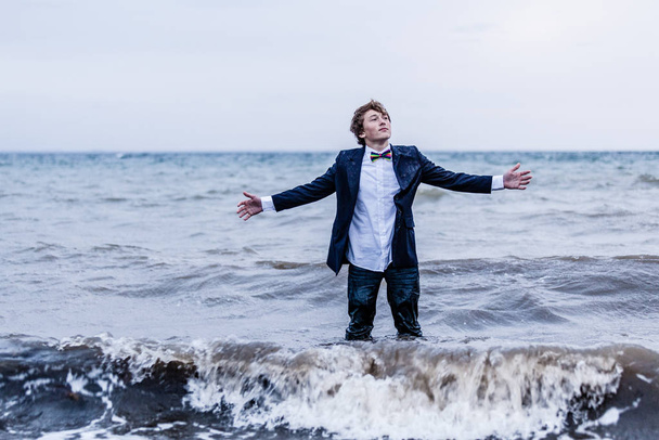 Thoughtful Young Man in Semi Formal Outfit, Standing at the Sea with Open Arms and Looking up. - Фото, зображення