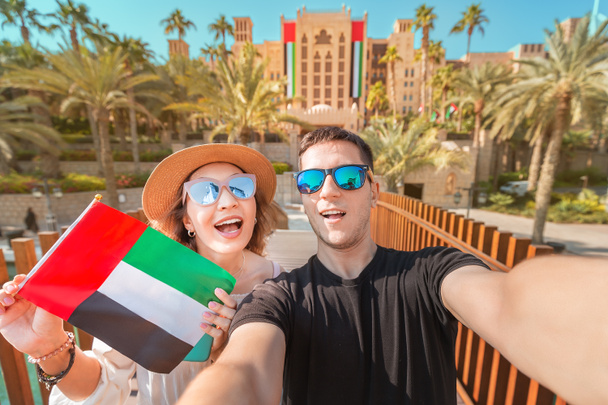 Selfie de um casal amoroso de homem e mulher segurando bandeira nacional dos Emirados Árabes Unidos. Viagem e imigração em Dubai e Emirados Árabes Unidos conceito
 - Foto, Imagem