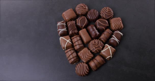 Čokoládové pralinky srdce ve tvaru na černém pozadí. Koncept Valentýna. Miluje čokoládu a sladkosti. Dolly shot 4k - Záběry, video