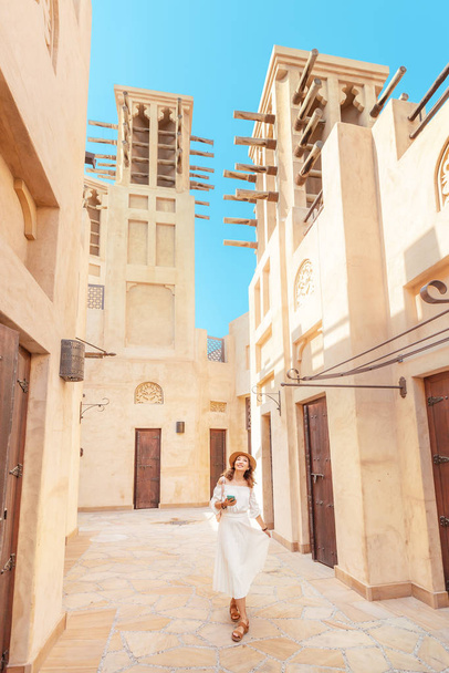 Happy asian girl in white dress walking among narrow streets of old town somewhere in Middle East. Travel destinations and tourism concept - Foto, Imagem