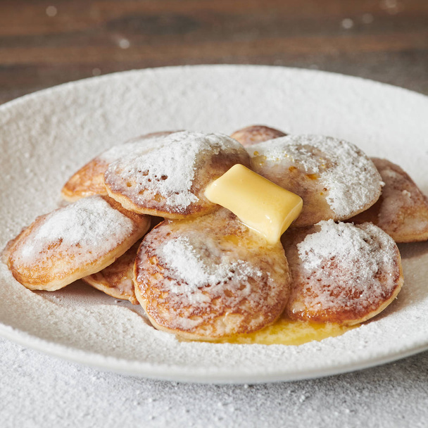 Mini crêpes hollandaises (Poffertjes). Mini crêpes moelleuses qui sont servies avec un gâchis de sucre en poudre et de beurre
. - Photo, image
