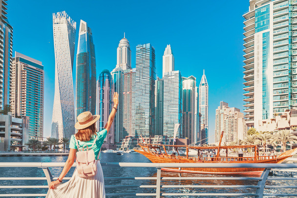 fröhliches asiatisches Reisemädchen, das auf einer Promenade im Yachthafenviertel Dubais spaziert. Reiseziele und touristischer Lebensstil in uae - Foto, Bild