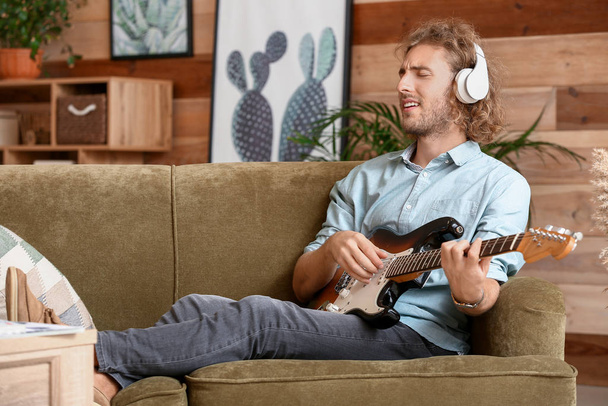 Чоловік грає на сучасній гітарі вдома
 - Фото, зображення