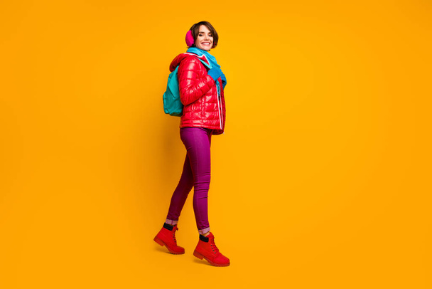 Фотографія повнометражного профілю красивої леді пішохідного хобі, що йде в гори з туристичною групою, носять казуальні червоні пальто чоботи сині шарфичні рукавички вушні обкладинки штанів ізольовані жовтого кольору фону
 - Фото, зображення