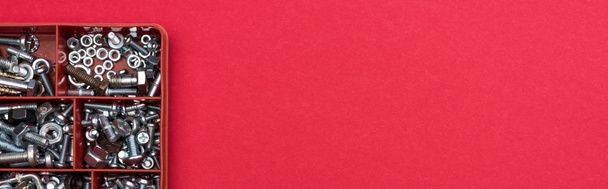 Vista dall'alto della cassetta degli attrezzi con dadi e viti in legno su fondo rosso, scatto panoramico
 - Foto, immagini