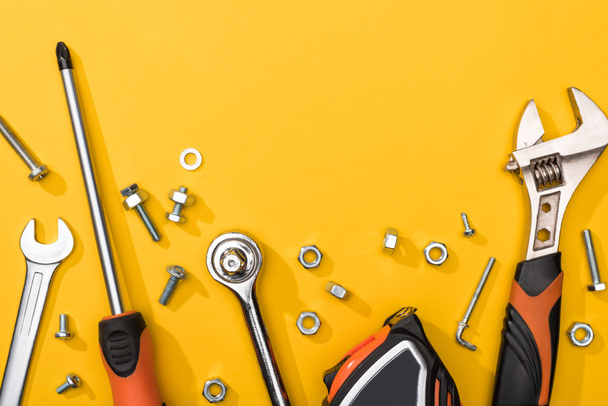 Top view of tool set with nuts and bolts on yellow background - Photo, Image