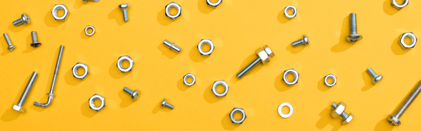 Top view of metal nuts and bolts on yellow background, panoramic shot - Foto, Imagem