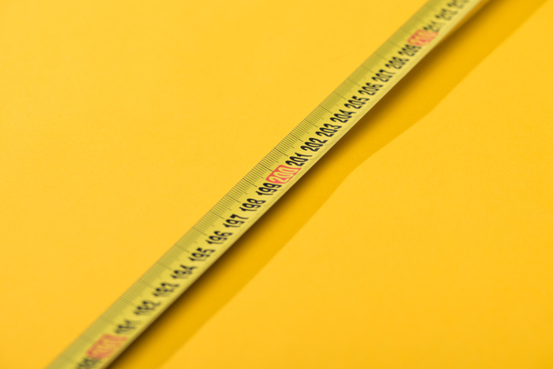 Vista de cerca de los números en cinta métrica industrial sobre fondo amarillo
 - Foto, imagen