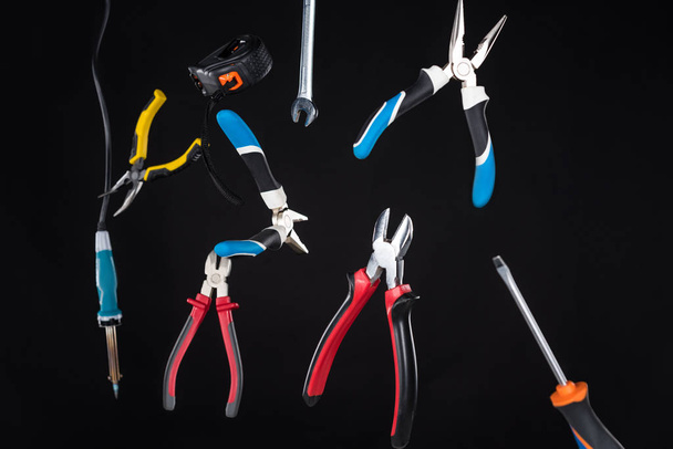 Набор инструментов с отверткой и плоскогубцами левитации в воздухе изолированы на черном
 - Фото, изображение