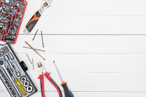 Werkzeugkoffer mit Schraubenschlüssel, Schraubendreher und Zange auf weißem Holzhintergrund - Foto, Bild