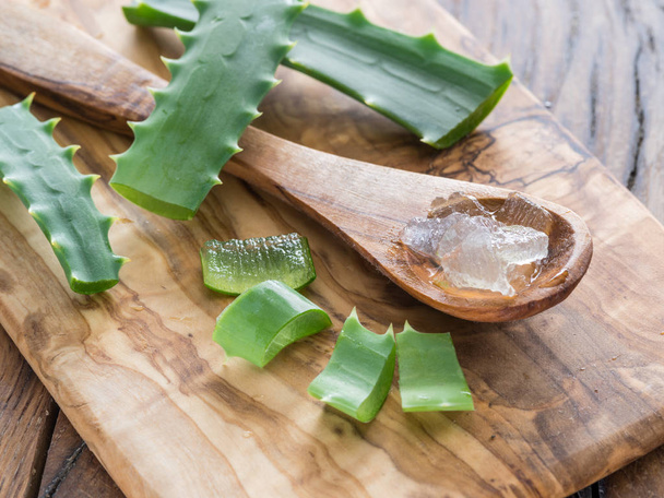 Fresh aloe leaves and aloe gel in the wooden spoon on the table. - Fotoğraf, Görsel