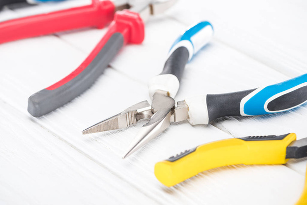 Close up view of metal pliers on white wooden background - Zdjęcie, obraz