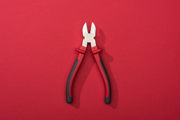 Top view of pliers with shadow on red background - Foto, Imagen