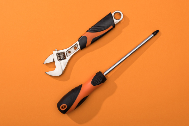 Top view of wrench and screwdriver on orange surface - Foto, Bild