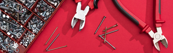 Top view of tool box with pliers and nails on red background, panoramic shot - Photo, Image