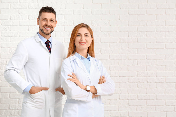Team of doctors on white brick background - Photo, Image