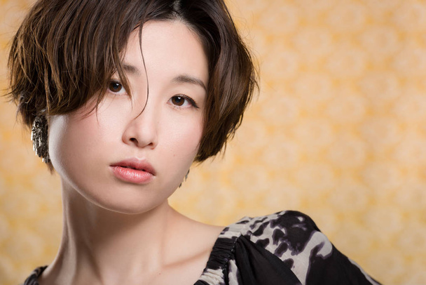 A portrait of a  young and beautiful Japanese woman shot on a yellow and white lace background. - Fotó, kép