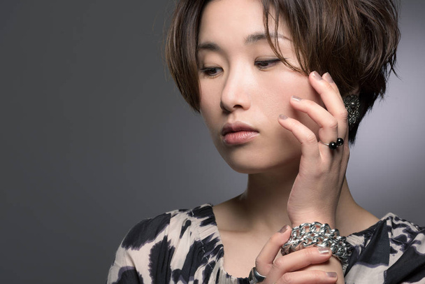 A portrait of a young, beautiful and very fashionable Japanese woman posed gently on a dark background. - Foto, Imagem