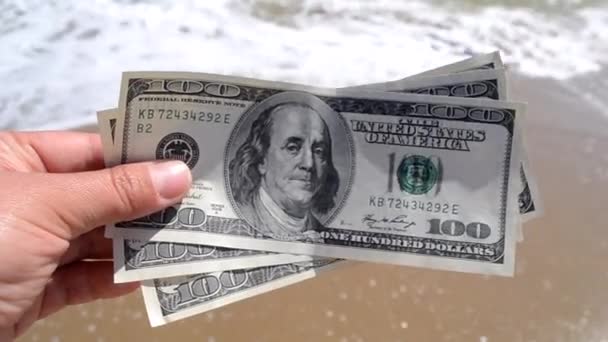 Lány kezében pénz számla 300 dollár a háttér a tenger óceán - Felvétel, videó